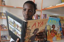 A girl reading Marguerite Abouet's comic book, 'Aya of Yopougon' A girl reading Marguerite Abouet's comic book, 'Aya of Yopougon'