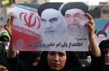 A supporter of the Iranian government holding a picture of founder of the Islamic Republic Ayatollah Ruhollah Khomeni, and supreme leader Ayatollah Ali Khamenei (AFP/Atta Kenare)