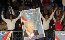 Iraqi refugees and supporters of former prime minister Iyad Allawi hold his poster during a campaign rally