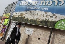 An Israeli ultra-orthodox Jewish man walks past a sign carrying the image of the east Jerusalem settlement of Ramat Shlomo on March 11. (AFP/File/Gali Tibbon)