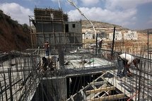 Palestinian labourers work at a construction site of new housing units in Givat Zeev Israeli settlement