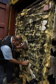 A Lebanese custom official collects packs of hashish confiscated from a container.