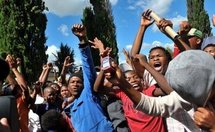 South Africans chant 'hero, hero' outside the court in Ventersdorp on 6th April as police escort one of the two men charged with the murder of white supremacist  Eugene Terre'Blanche. (AFP/File/Alexander Joe)