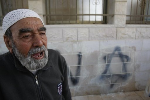 A Palestinian man stands next to the graffiti.  (AFP/Jaafar Ashtiyeh)