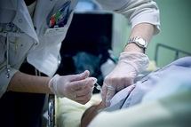 A doctor administers a shot to a patient at a hospital ER unit. A doctor administers a shot to a patient at a hospital ER unit.