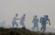 Palestinian protesters run for cover from Israeli tear gas during a demonstration