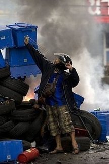 A Thai demonstrator uses a slingshot to launch stones against security forces during clashes in Bangkok.