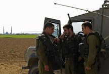 An Israeli soldier talks on his radio as he stands with fellow soldiers near the border with the Gaza strip.