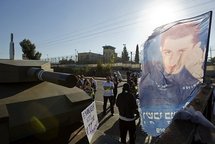 Israeli protesters stand next to a flag showing the picture of captured Israeli soldier Gilad Shalit.