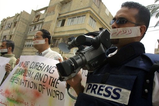 Palestinian journalists protest with stickers reading 'Don't shut journalists' mouths' at a refugee camp in Gaza.