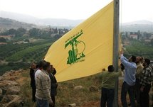 Hezbollah supporters place a Hezbollah flag in front of the Israeli settlement of Metulla on the Lebanese-Israeli border.